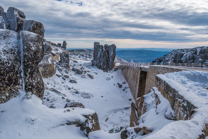 Landscape with granite rocks, road and bridge and mountains on the horizon on a cloudy day, Serra da Estrela Natural Park PORTUGAL