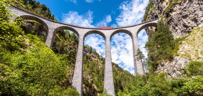 Landscape with Landwasser Viaduct in summer, Filisur, Switzerland. Panoramic view of high railroad bridge and red train