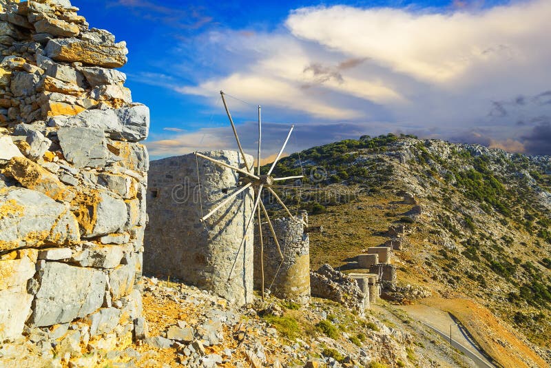 Landscape with old traditional mill in mountain valley with incredible sunset clouds and sun. Crete, Greek Island