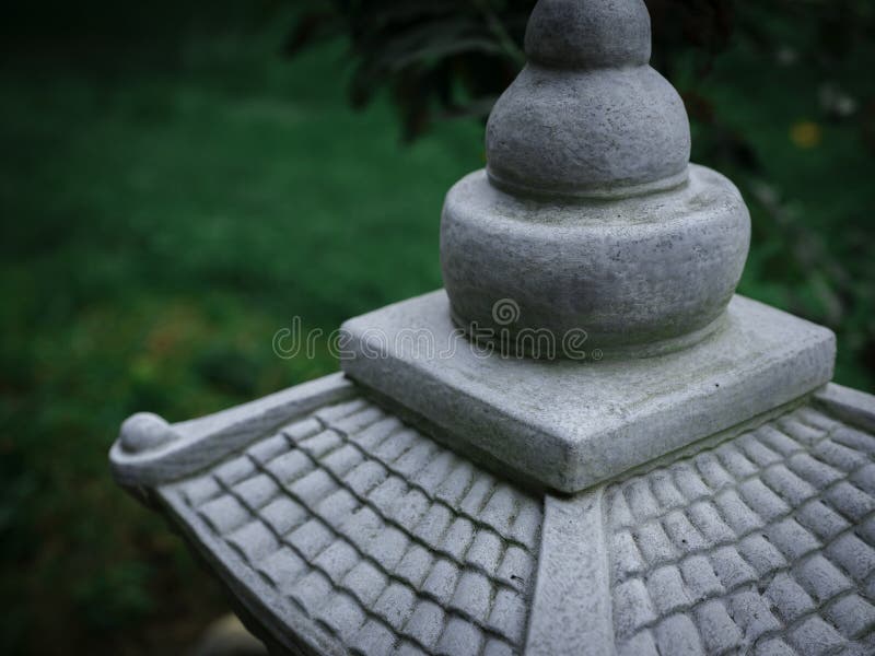 Japanese miniature pagoda in the garden. Rooftop closeup view with blurred green yard in the background.
