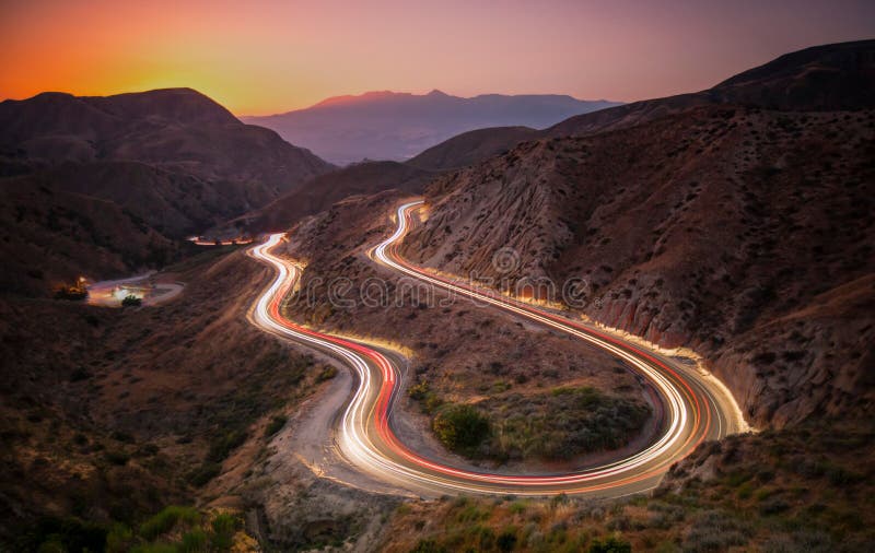 Landscape of roads on hills with long exposure car trails during a beautiful sunset