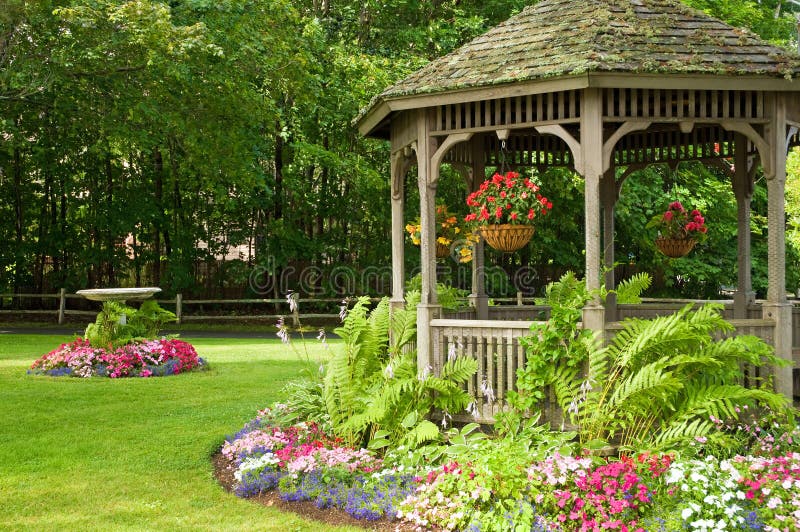 Landscaping gazebo in park. Landscaping around a gazebo with hanging flower baskets in a quiet park stock image