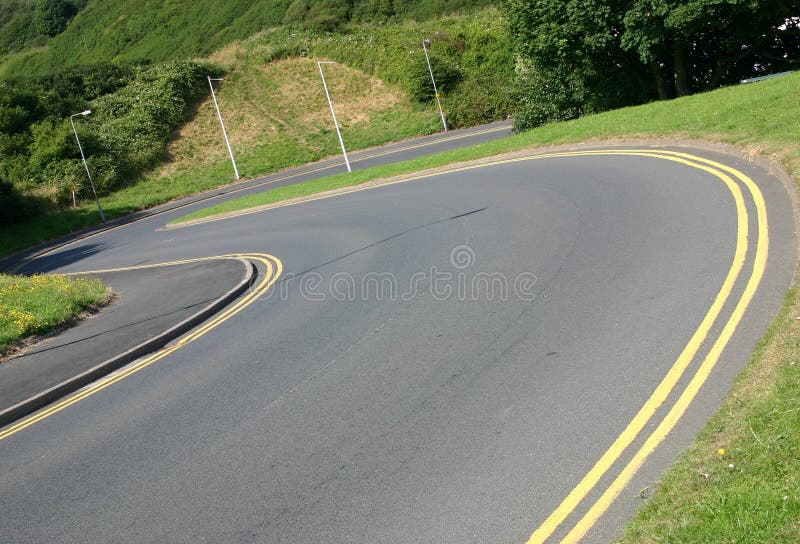 A bendy country road going downhill. A bendy country road going downhill