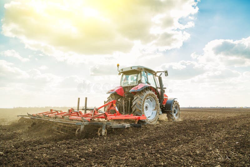 Farmer in tractor preparing land with seedbed cultivator as part of pre seeding activities in early spring season of agricultural works at farmlands. Farmer in tractor preparing land with seedbed cultivator as part of pre seeding activities in early spring season of agricultural works at farmlands.