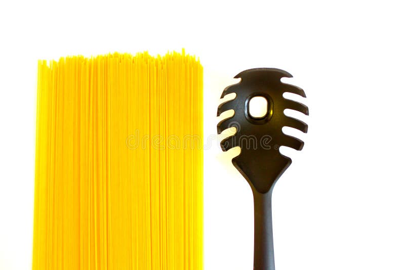 Lange ruwe gele spaghetti en zwarte die lepel met gat op wit wordt geïsoleerd stock afbeeldingen Lange ruwe gele spaghetti en zwarte die lepel met gat op wit wordt geïsoleerd stock afbeeldingen