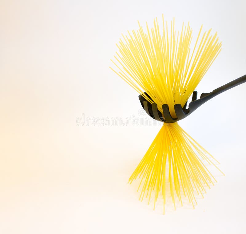 Lange ruwe gele spaghetti in zwarte plastic die lepel op wit wordt geïsoleerd stock foto Lange ruwe gele spaghetti in zwarte plastic die lepel op wit wordt geïsoleerd stock foto