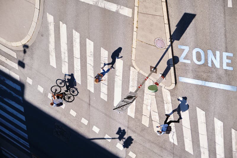 Lange Schatten von Menschen, die an einem Schnittpunkt zu Fuß oder mit dem Fahrrad gehen - Luftsicht lizenzfreie stockfotos Lange Schatten von Menschen, die an einem Schnittpunkt zu Fuß oder mit dem Fahrrad gehen - Luftsicht lizenzfreie stockfotos
