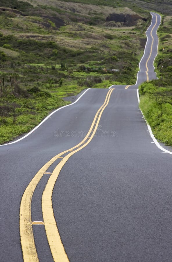 An isolated road winds through a green landscape. An isolated road winds through a green landscape.