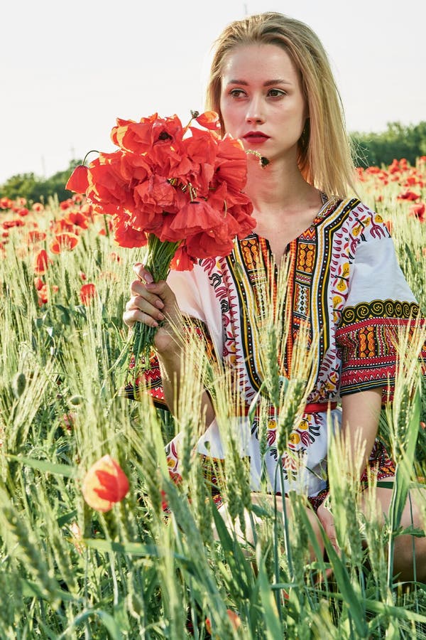 Langharig blonde jonge vrouw in een witte korte kleding op een gebied van groene tarwe en wilde papavers royalty-vrije stock foto Langharig blonde jonge vrouw in een witte korte kleding op een gebied van groene tarwe en wilde papavers royalty-vrije stock foto