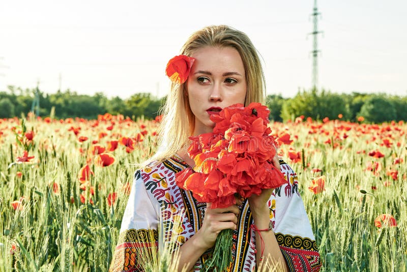 Langharig blonde jonge vrouw in een witte korte kleding op een gebied van groene tarwe en wilde papavers royalty-vrije stock fotografie Langharig blonde jonge vrouw in een witte korte kleding op een gebied van groene tarwe en wilde papavers royalty-vrije stock fotografie