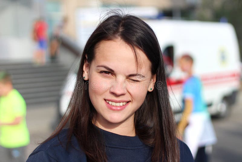 langharig donkerbruin meisje die in het vierkant op de achtergrond van een ziekenwagen glimlachen Portret van Europese vrouw in b royalty-vrije stock fotografie langharig donkerbruin meisje die in het vierkant op de achtergrond van een ziekenwagen glimlachen Portret van Europese vrouw in b royalty-vrije stock fotografie