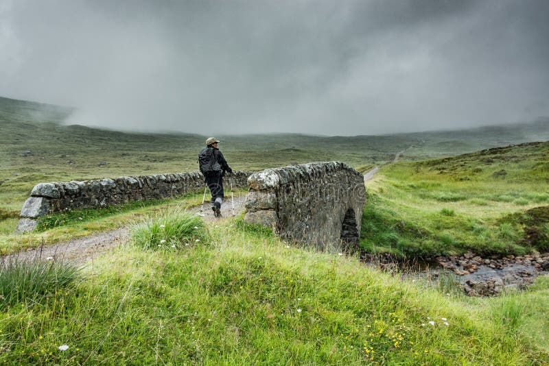 A hiker walks on an old stone bridge on the hiking trail which takes an old military road. A hiker walks on an old stone bridge on the hiking trail which takes an old military road