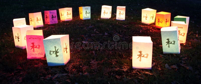 A circle of colorful candlelit paper lanterns on leafy ground at night. A circle of colorful candlelit paper lanterns on leafy ground at night.