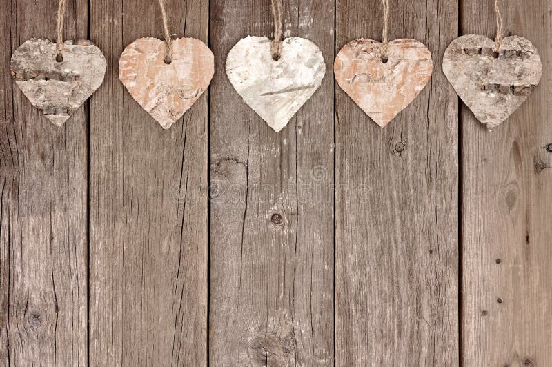 Rustic birch bark heart ornaments hanging against a vintage wooden background. Rustic birch bark heart ornaments hanging against a vintage wooden background