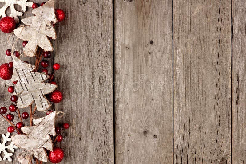 Rustic Christmas side border with wood ornaments and berries on an aged wood background. Rustic Christmas side border with wood ornaments and berries on an aged wood background