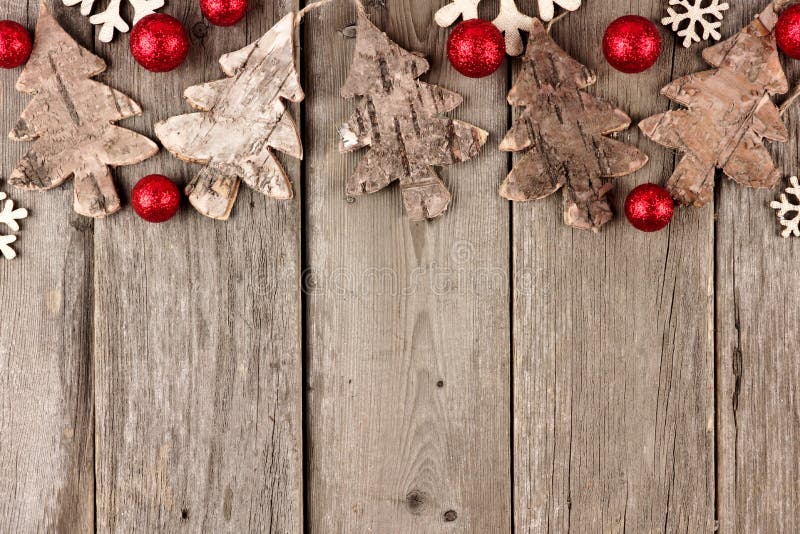 Rustic Christmas top border with wood ornaments and red baubles on an aged wood background. Rustic Christmas top border with wood ornaments and red baubles on an aged wood background