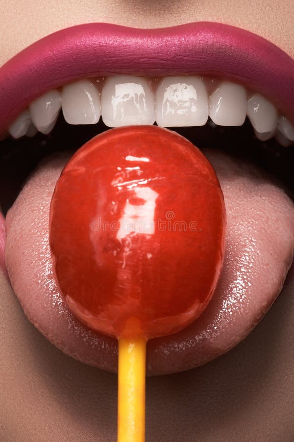 Lanzamiento macro del encanto con los labios de la mujer atractiva con una piruleta dulce del caramelo fotos de archivo Lanzamiento macro del encanto con los labios de la mujer atractiva con una piruleta dulce del caramelo fotos de archivo
