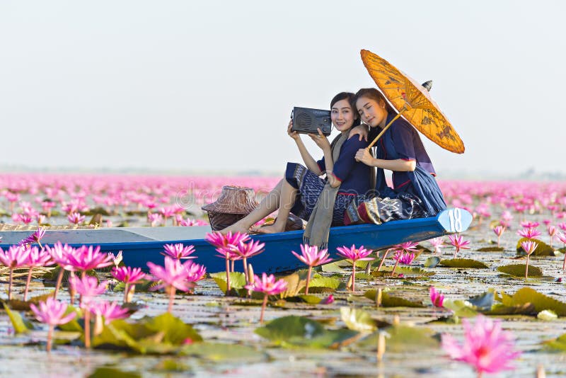 Laos woman listening radio on boat in flower lotus lake, Woman wearing traditional Thai people , Red Lotus Sea UdonThani Thailand royalty free stock photography Laos woman listening radio on boat in flower lotus lake, Woman wearing traditional Thai people , Red Lotus Sea UdonThani Thailand royalty free stock photography