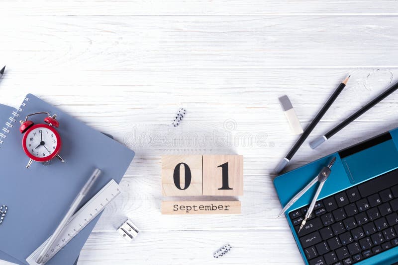 Laptop, red alarm clock and supplies, wooden calendar with date 1st September. on white desk. Back to school concept. flat lay. Laptop, red alarm clock and supplies, wooden calendar with date 1st September. on white desk. Back to school concept. flat lay.