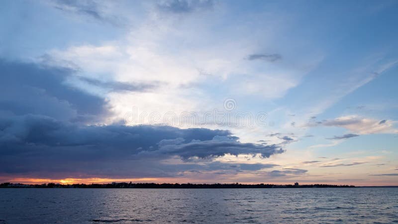 Laps de temps de coucher du soleil avec les nuages mobiles le long du lac
