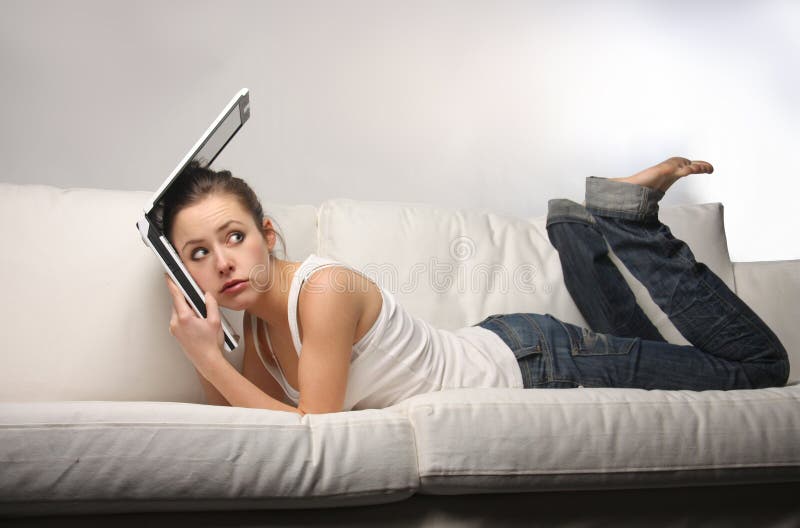 Young woman with sad expression on sofa with laptop