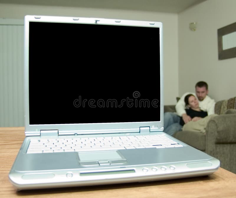 A silver laptop on a wood table with a blank screen ready for your copy. Very shallow DOF, focus is on the screen itself, the man and the woman in the background are very out of focus. A silver laptop on a wood table with a blank screen ready for your copy. Very shallow DOF, focus is on the screen itself, the man and the woman in the background are very out of focus.