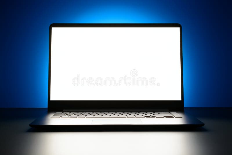 The laptop is on a blue background with a glowing white screen with copy space royalty free stock photos