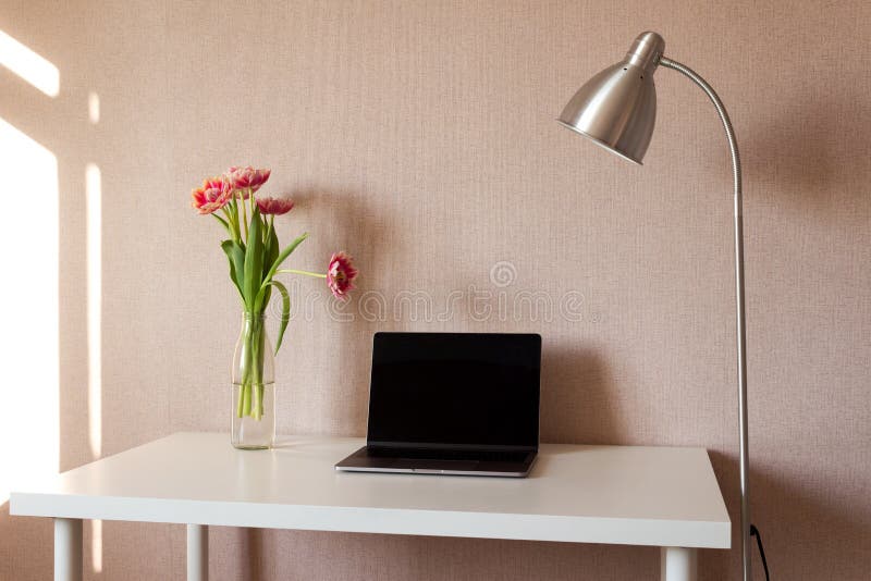 Laptop, boeket van tulpen en metaallamp op witte lijst royalty-vrije stock afbeeldingen Laptop, boeket van tulpen en metaallamp op witte lijst royalty-vrije stock afbeeldingen