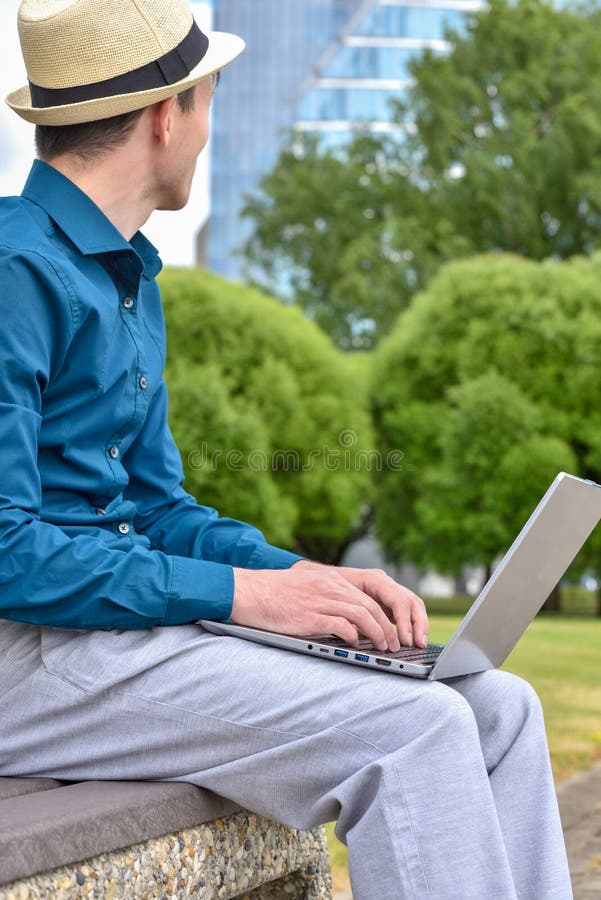 Laptop computer on a programmer`s lap while working remotely outside the office. Man with a laptop works remotely