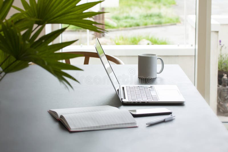 Laptop Computer on a Table with Coffee Mug, Notepad, Mobile Phone and Pencil. Stock Photo