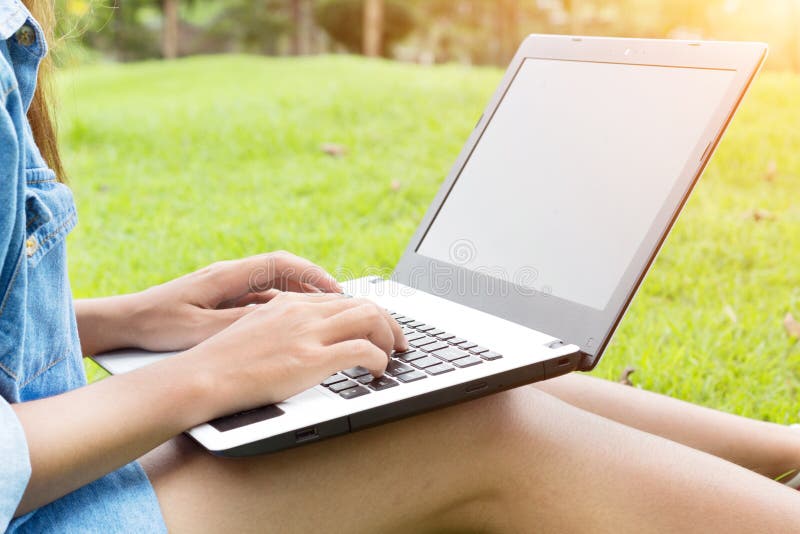 Laptop do uso da mulher no parque fotografia de stock Laptop do uso da mulher no parque fotografia de stock