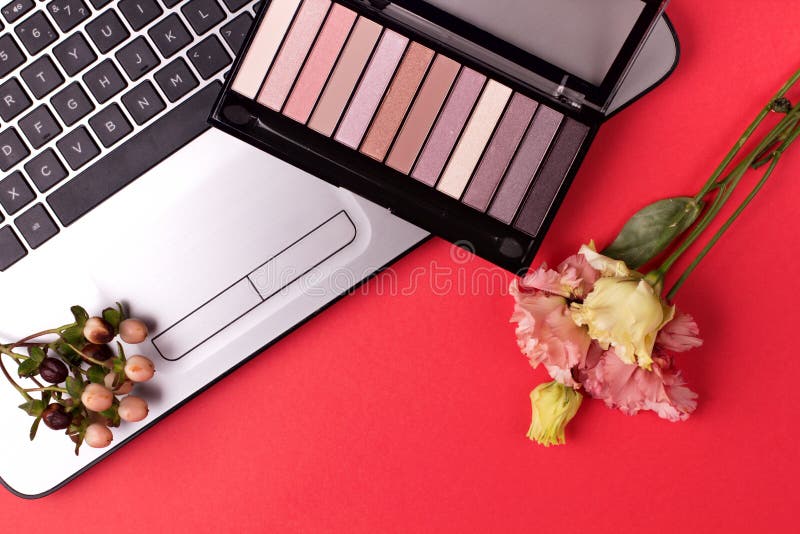 Laptop with Flowers and Cosmetics on Table. Freelancer Workspace Stock
