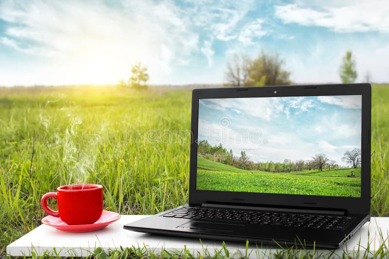 Laptop i filiżanka gorąca kawa na tło malowniczej naturze