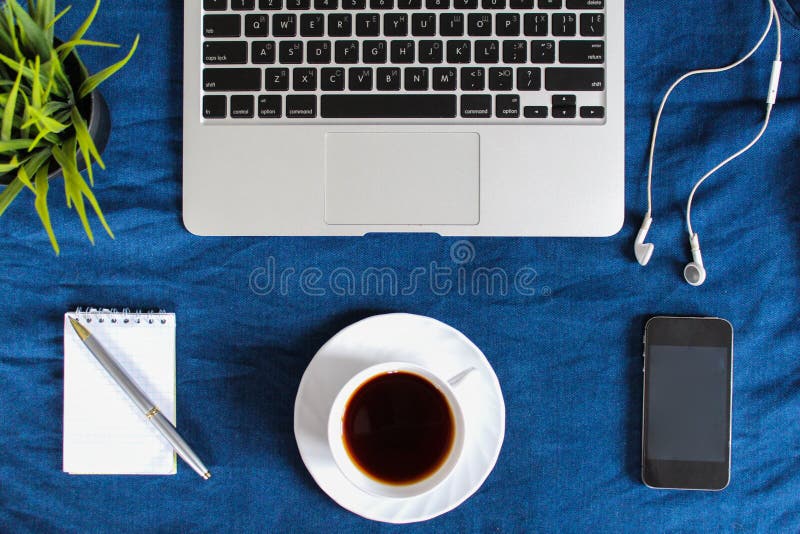 Laptop klawiatura, biała filiżanka herbata na spodeczku, notepad, pióro i zielona roślina w kącie na zmroku, - błękitny zmięty ca obraz royalty free