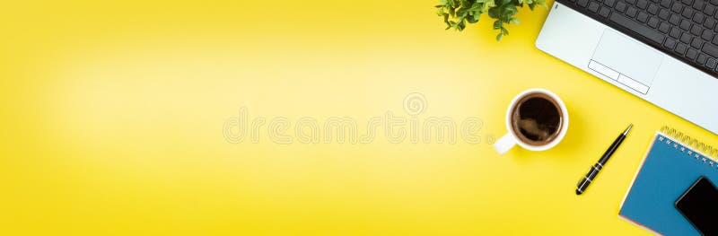 Laptop, notebook, smartphone, coffee and pen on yellow background. Office desk table with modern accessories banner