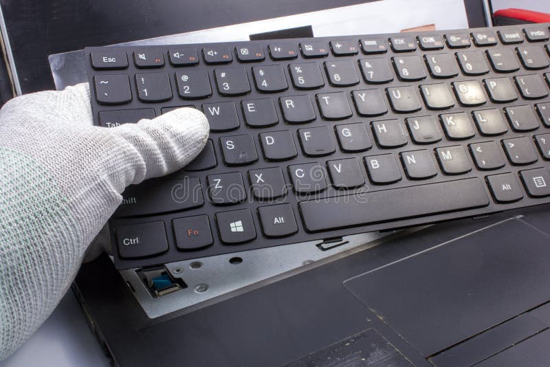 Laptop repair. The service technician disassembles the old, damaged keyboard stock photo