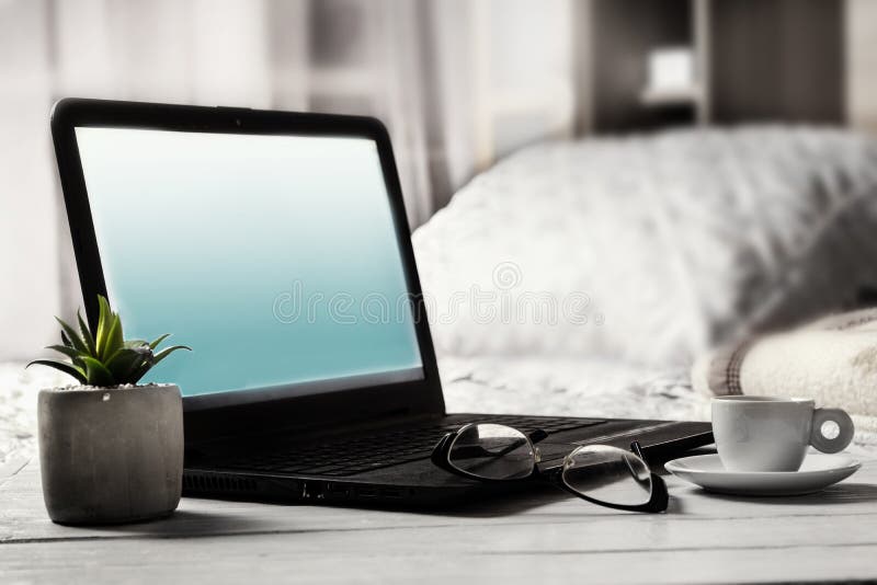 Laptop z pustym ekranem obok szkieł i filiżanka kawy na wezgłowie stole w sypialni zdjęcia royalty free Laptop z pustym ekranem obok szkieł i filiżanka kawy na wezgłowie stole w sypialni zdjęcia royalty free