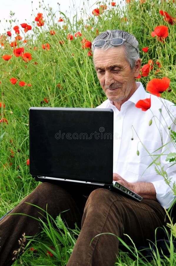 Senior farmer man enjoys working on laptop in the countryside. Senior farmer man enjoys working on laptop in the countryside