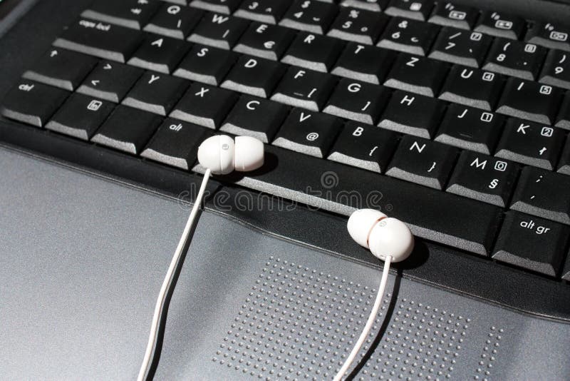 Close up shot of laptop and earphone, presenting listening to music on computer. Close up shot of laptop and earphone, presenting listening to music on computer