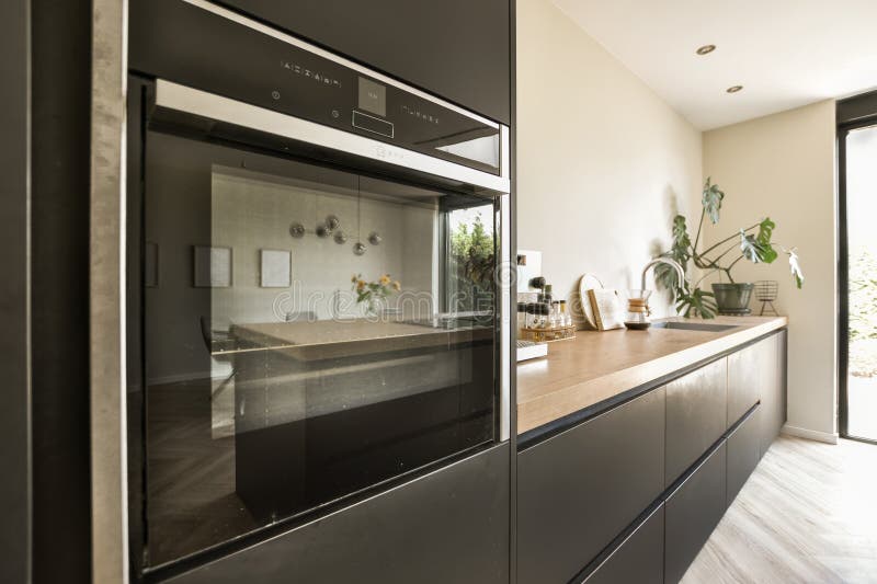 a modern kitchen with wood counter tops and stainless steel oven hoods on the wall behind it is an open door. a modern kitchen with wood counter tops and stainless steel oven hoods on the wall behind it is an open door
