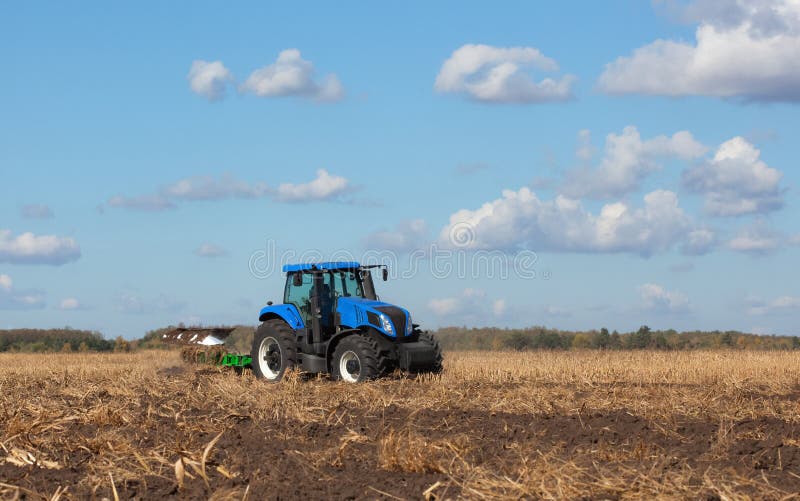 A large blue tractor, plowing field against the beautiful sky. royalty free stock photography A large blue tractor, plowing field against the beautiful sky. royalty free stock photography