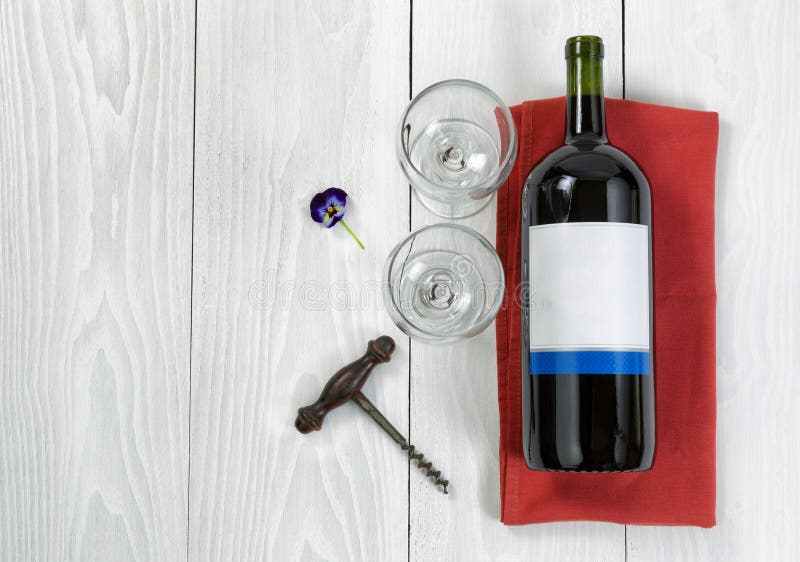 Large bottle of red wine on serving napkin with glasses on white