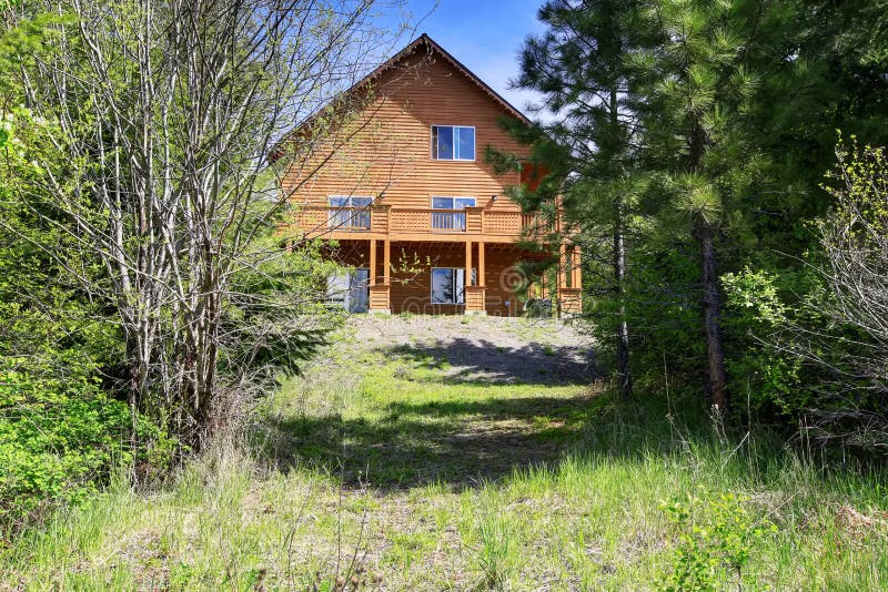 Large Cabin style home in the woods with lots of greenery. Large Cabin style home exterior in the woods with lots of greenery royalty free stock photo Large Cabin style home in the woods with lots of greenery. Large Cabin style home exterior in the woods with lots of greenery royalty free stock photo