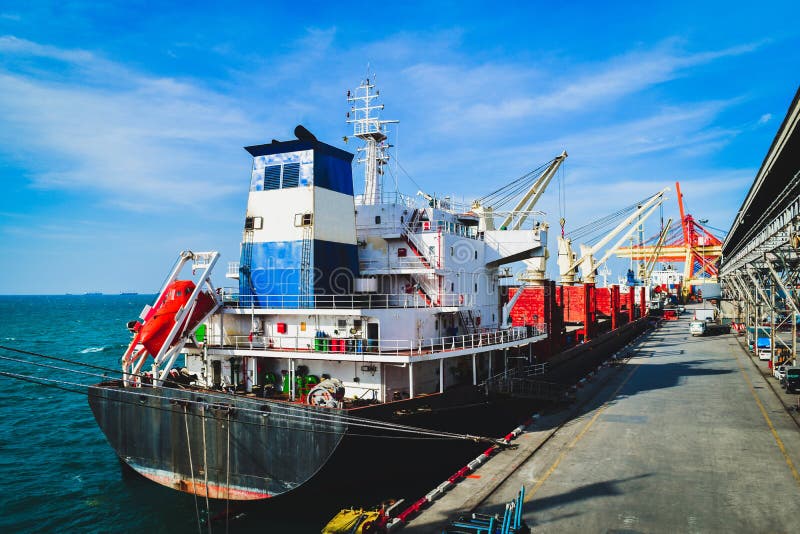 Large Cargo Ship Loading And Unloading Cargo At Seaport Stock Photo