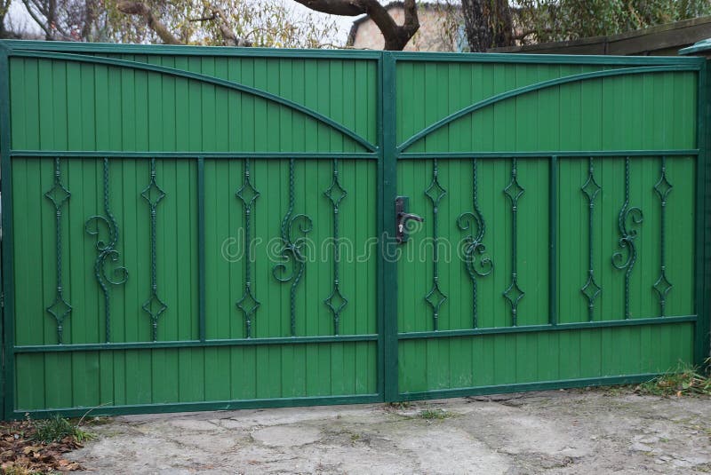 Large Closed Green Metal Gate with Wrought Iron Pattern Stock Photo