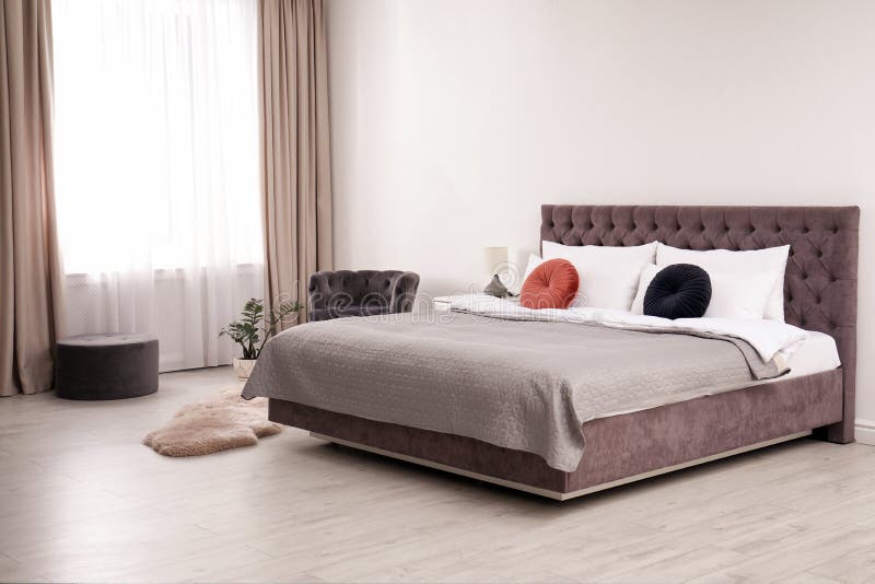 Large Comfortable Bed Near Light Wall in Simple Room Stock Image