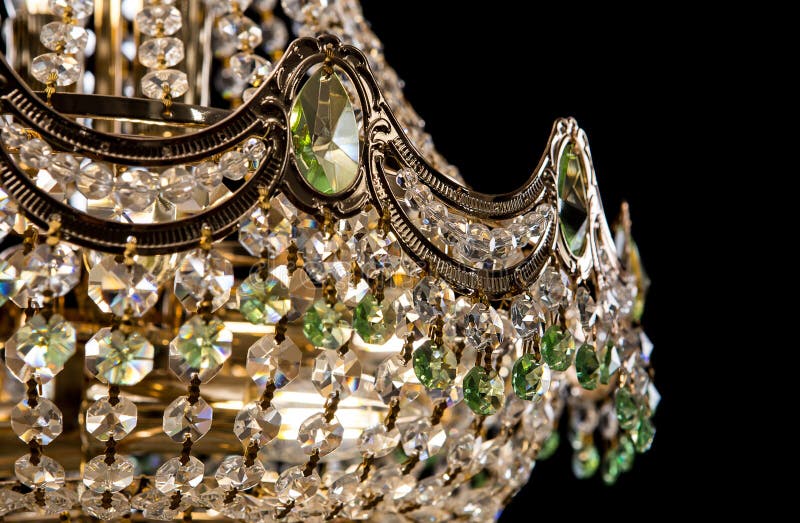 Large crystal chandelier close-up with green crystals isolated on black background.