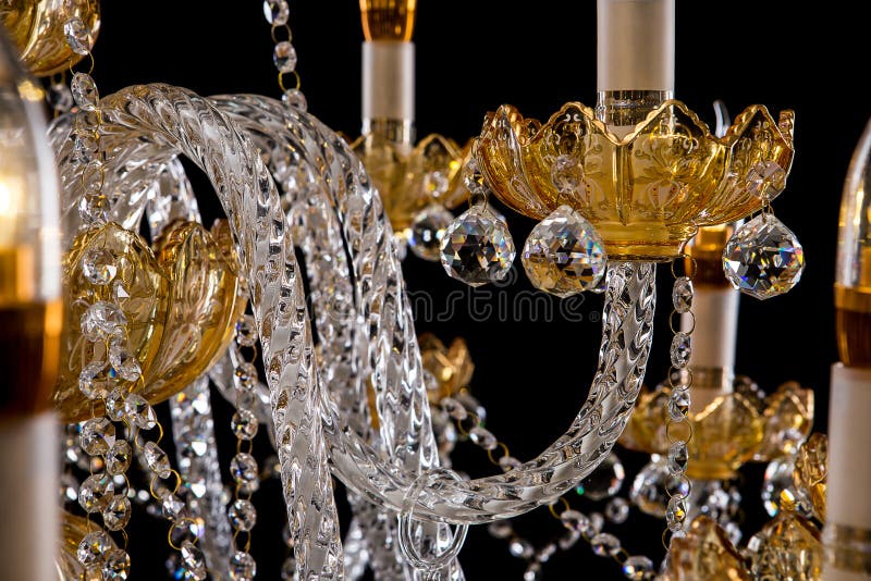 Large crystal close-up chandelier with candles isolated on black background.