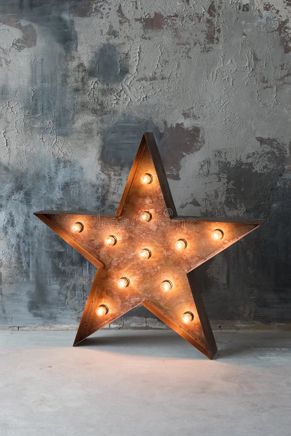 Large decorative retro star with lots of burning lights on grunge concrete background. Beautiful decor, modern design element. The loft style studio