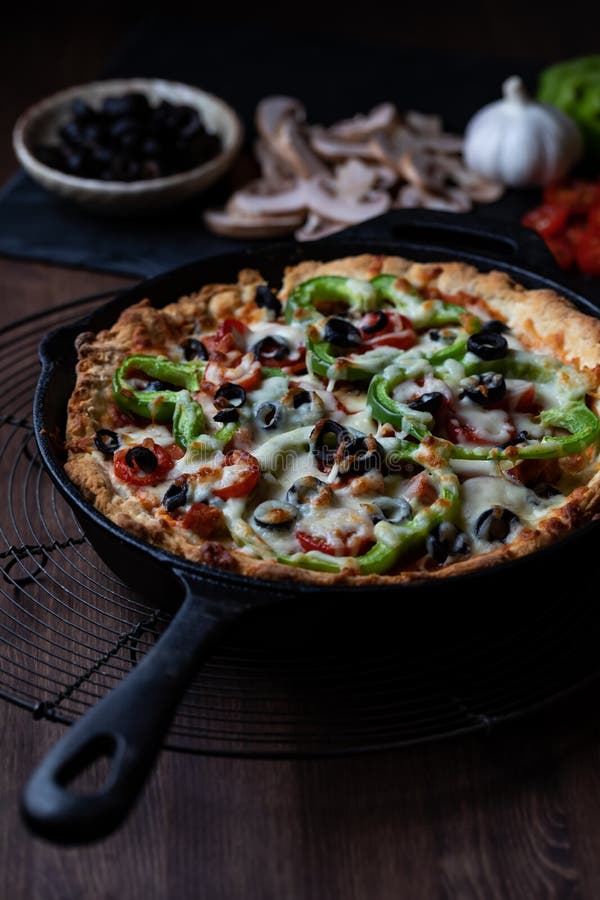 Large Deluxe Deep Dish Pan Pizza Against a Dark Background. Stock Photo